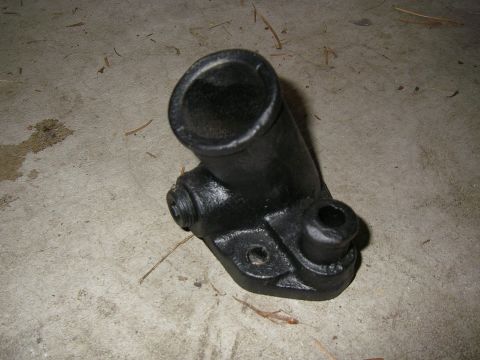 1990 Ford Bronco - A black metal automotive part, possibly a clutch master cylinder or similar component, rests on a concrete surface.