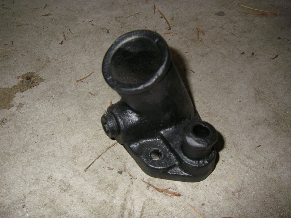 Black metal automotive part with a pipe-like opening and mounting holes