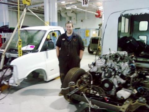 1989 Ford Bronco - A person stands next to a disassembled white van chassis with its engine nearby in the foreground.