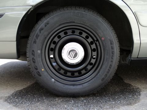 2001 Mercury Grand Marquis - A close-up shot focuses on the steel wheel and tire of a Mercury vehicle, the brand's emblem on the hubcap.