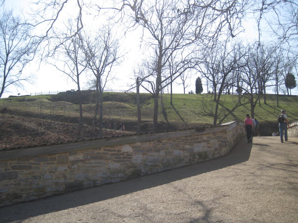 Stone wall and pathway at Antietam Battlefield with bare trees and a grassy hill