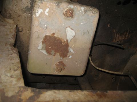 1979 Ford Bronco - Close-up view of a rusty underbody component with chipped paint and visible screws.