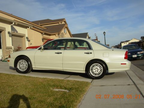 1999 Mitsubishi Diamante - A white sedan is parked on a driveway next to a house, with another car visible in the background.