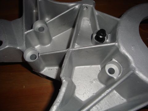 1989 Ford Bronco - This is a close-up view of a metal bracket, possibly for an engine component, with visible bolt holes.