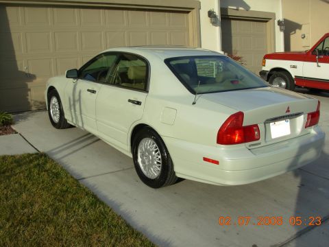 1999 Mitsubishi Diamante - A white sedan is parked in a driveway with a red and white truck in the background. The timestamp on the photo indicates it was taken on Fe…