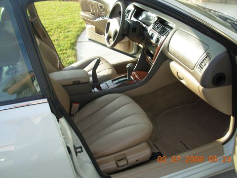 1999 Mitsubishi Diamante - The interior of a car shows tan leather seats, wood trim accents, and a floor mat with the word DIAMANT.