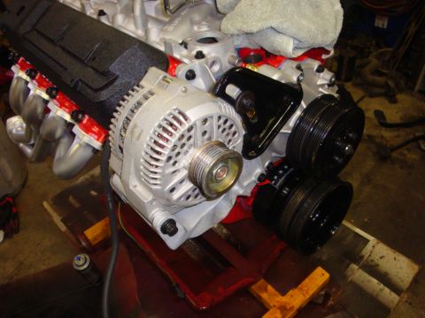 1989 Ford Bronco - Close-up view of an engine block an alternator and multiple pulleys, likely during a repair or upgrade.