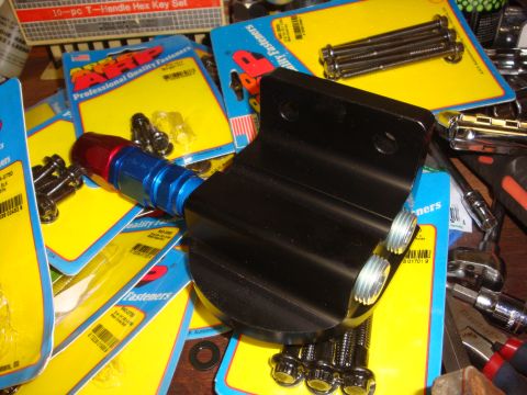 1989 Ford Bronco - A collection of automotive parts, including an oil filter adapter and various fasteners, are laid out on a surface.