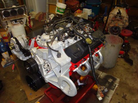 1989 Ford Bronco - A disassembled engine sits on a red stand, surrounded by various tools and parts in a workshop.