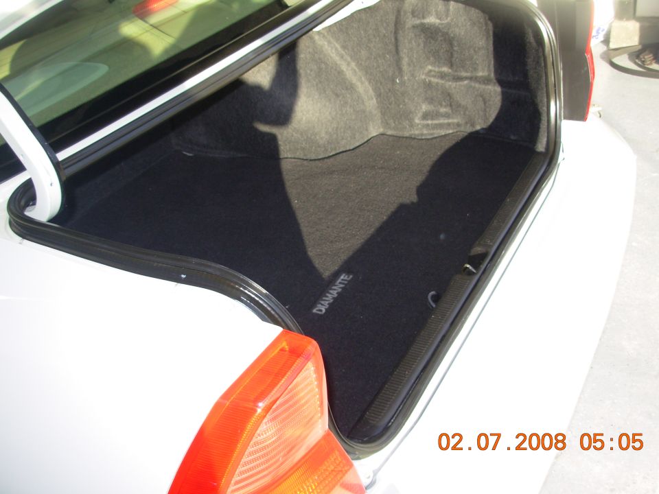 White car trunk interior with a black mat that says DIAMANTE. A red taillight is visible
