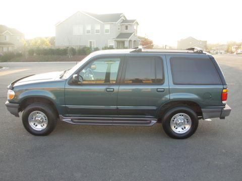 1997 Ford Explorer - The side profile of a green 1997 Ford Explorer is shown with tinted windows and running boards.