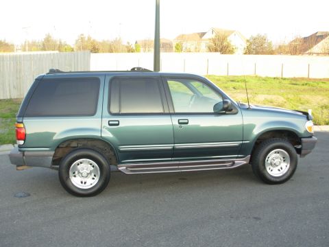 1997 Ford Explorer - Side view of a green SUV with tinted windows and running boards.