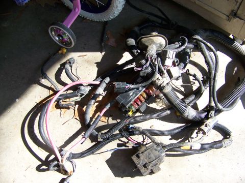 1992 Jeep YJ - A complex automotive wiring harness lies on the ground, a fuse box and numerous connectors.