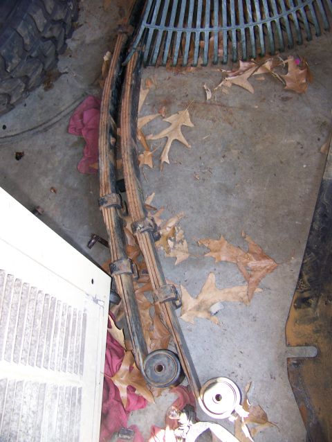 1992 Jeep YJ - Leaf springs are shown on a concrete surface, scattered with fallen leaves and a portion of a tire.