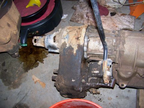 1992 Jeep YJ - A heavily soiled Jeep transmission and transfer case assembly is shown on a garage floor, with evidence of an oil leak.