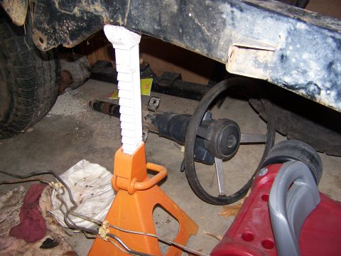 1992 Jeep YJ - Frame and steering column assembly on jack stands, with a tire and some parts on the floor.