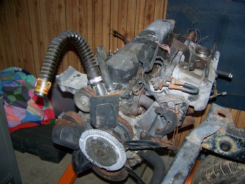 1992 Jeep YJ - Engine assembly shown on an orange stand, with a flexible hose and fan blade visible. Text on the hose indicates it is a part from a vehicl…