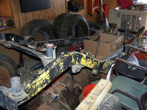 1992 Jeep YJ - A disassembled Jeep frame and spare tires are stored indoors amidst various other items.