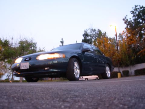 1995 Ford Taurus - A dark green 1995 Ford Taurus sedan is parked outdoors under a streetlamp.