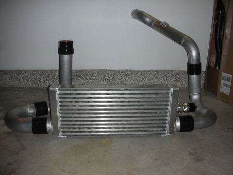 1998 Ford Crown Victoria - aluminum front-mount intercooler with several mandrel-bent charge pipes and silicone couplers laid out on a garage floor.