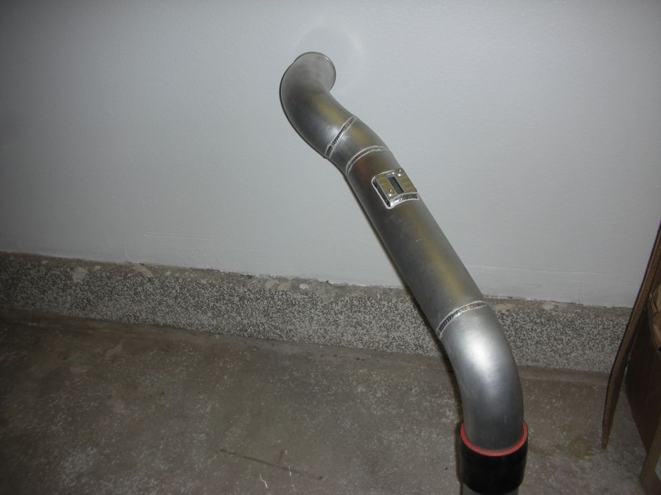 S-shaped polished aluminum pipe with welded bracket leaning against a wall