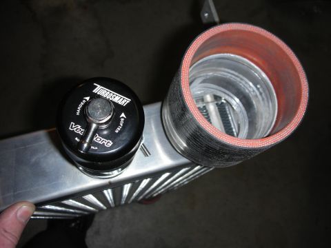 1998 Ford Crown Victoria - close-up of a black Turbosmart blow-off valve mounted near an aluminum tube fitted with a red-lined silicone coupler.