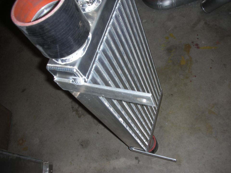 Aluminum intercooler with welded support bar and black coupler on shop floor