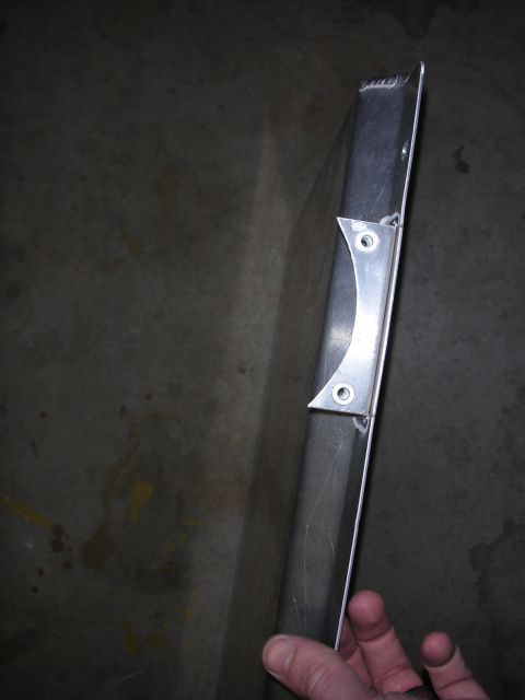 1998 Ford Crown Victoria - hand holds a long aluminum extrusion fitted with a welded mounting bracket above a stained concrete floor.