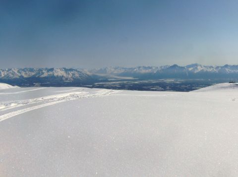 2000 Ford E350 - A vast snowy landscape stretches towards a distant mountain range under a clear blue sky.