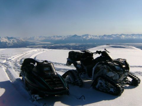 2000 Ford E350 - Snowmobiles and an ATV are parked in a snowy mountain landscape under a clear blue sky.