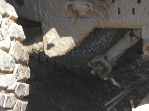 1995 Ford Bronco - The undercarriage of a vehicle is covered in mud, suggesting it has been driven off-road.