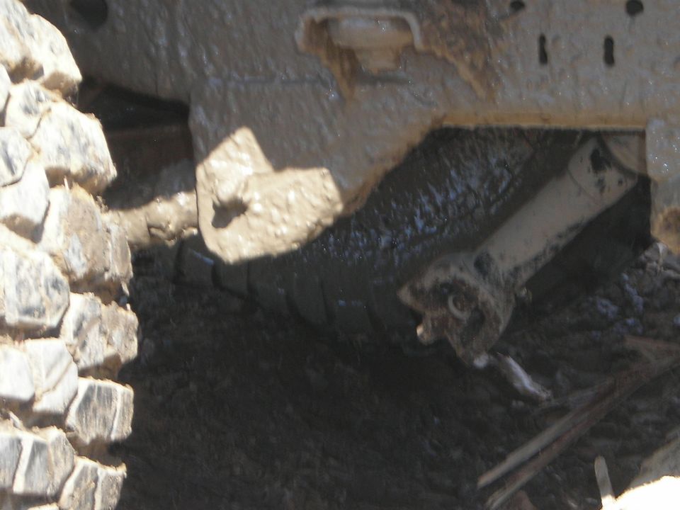 close-up of a muddy tire and suspension components of an off-road vehicle