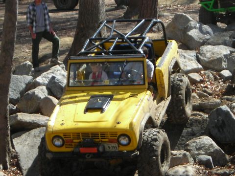 1995 Ford Bronco - This modified SUV is navigating a challenging rocky terrain with its occupants inside.