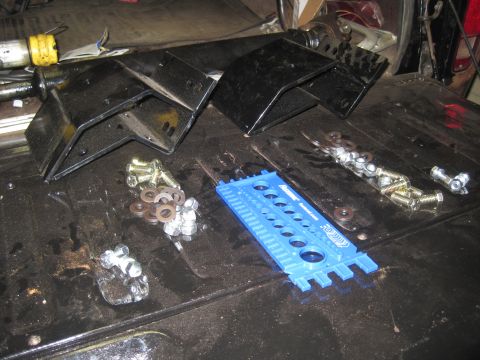 1979 Ford Bronco - Suspension brackets and hardware are organized on a workbench, ready for installation.