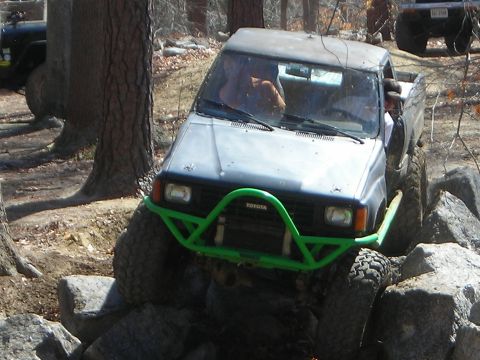 1995 Ford Bronco - A Toyota pickup truck tackles a rocky trail, with another vehicle visible in the background.