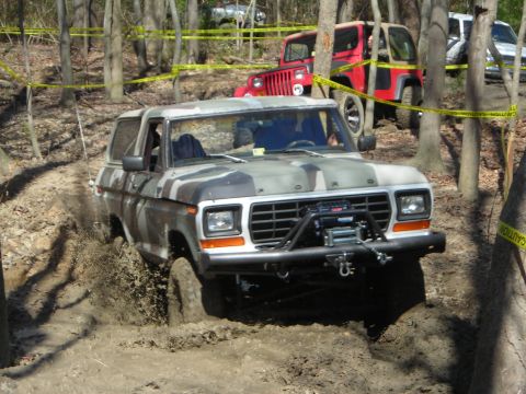 1995 Ford Bronco - This Ford Bronco navigates a muddy off-road course with other vehicles visible in the background.