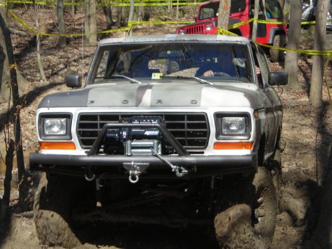 1995 Ford Bronco - This Ford Bronco, likely from the late 1970s, is equipped for off-road adventures with a winch and large tires, seen here navigating a mudd…