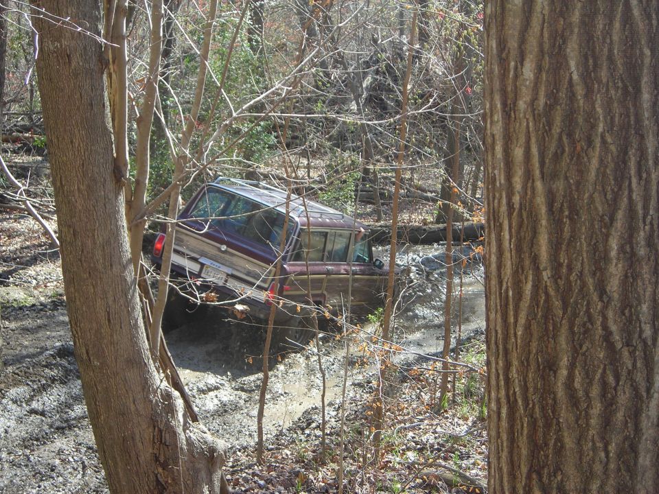 1995 Ford Bronco stuck in a muddy ditch off-road, seen from the side