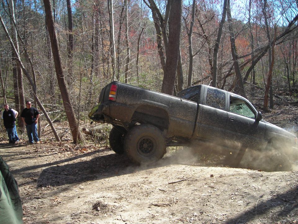 Muddy pickup truck driving off-road, kicking up dust