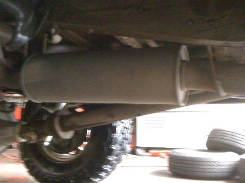 1996 Ford C-350 (Centurion Conversions) - Close-up view of the exhaust system of a vehicle, focusing on the muffler and pipes.