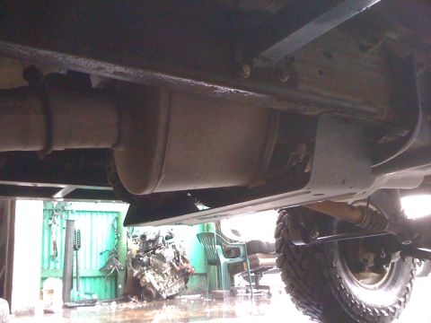 1996 Ford C-350 (Centurion Conversions) - A view of the exhaust system and undercarriage of a vehicle, with a tire visible on the right.