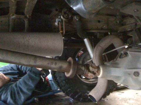 1996 Ford C-350 (Centurion Conversions) - A close-up view of the undercarriage of a vehicle, focusing on the exhaust system and drivetrain components.