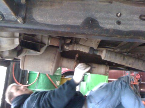 1996 Ford C-350 (Centurion Conversions) - Mechanic working on the exhaust system underneath a vehicle.