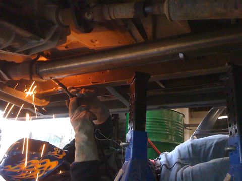 1996 Ford C-350 (Centurion Conversions) - Welding sparks fly as a straight pipe exhaust is installed on a vehicle.