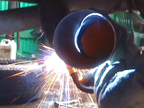 1996 Ford C-350 (Centurion Conversions) - Welding sparks illuminate an exhaust pipe during repair work.