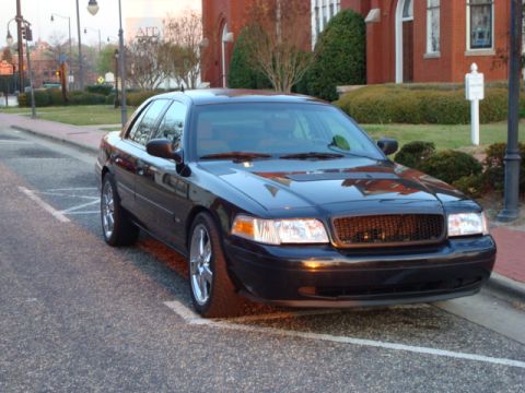 2004 Ford Crown Victoria - Black 2004 Ford Crown Victoria parked curbside in front of a brick building.