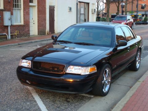 2004 Ford Crown Victoria - A black sedan is parked on a street with a red SUV visible in the background.