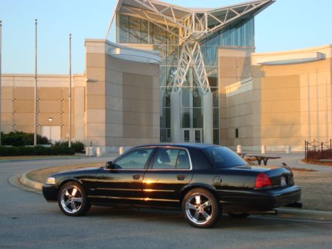 2004 Ford Crown Victoria - Black 2004 Ford Crown Victoria parked in front of a contemporary building during golden hour.
