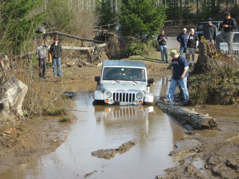 2008 Jeep Wrangler - Jeep Wrangler navigates a challenging muddy obstacle course with onlookers.