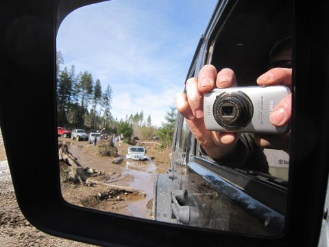 2008 Jeep Wrangler - Several off-road vehicles navigate a challenging muddy trail, with one Jeep stuck in the mire.